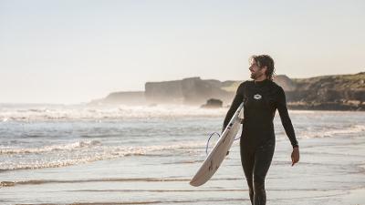 Surfer walking along Sandhaven Beach